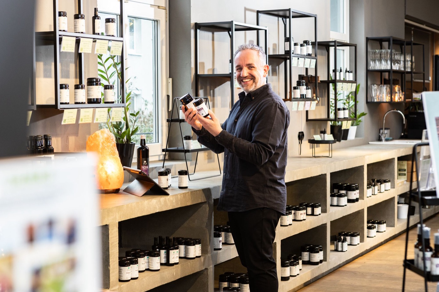 Enrico Mandl im NUI Shop in Dornbirn mit zwei NUI Produkten in der Hand