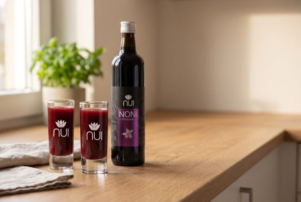 Botella de NUI NONI Original junto a dos vasos llenos de 60 ml sobre una mesa de cocina por la mañana