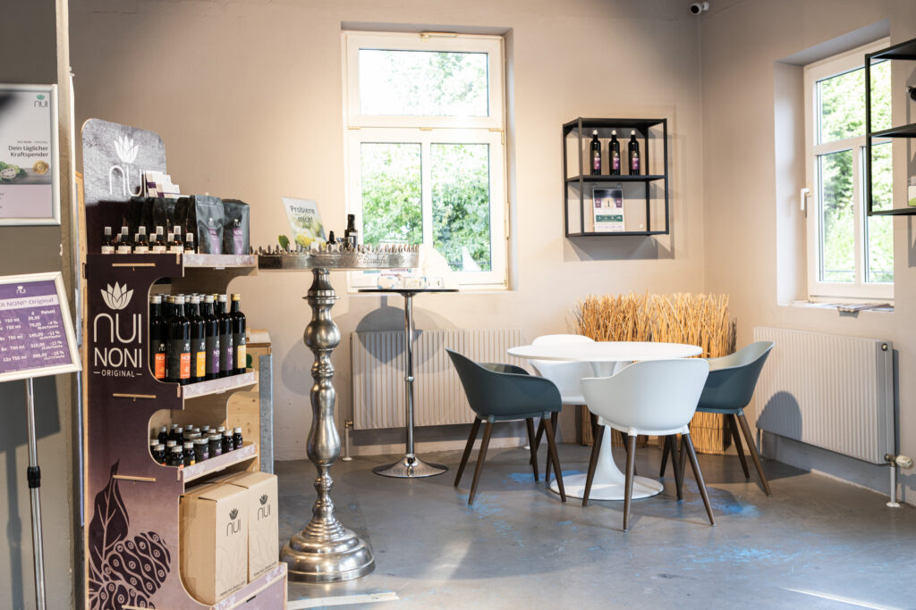 Rincón con mesa redonda y sillas en la tienda NUI de Dornbirn, junto a una mesa de degustación